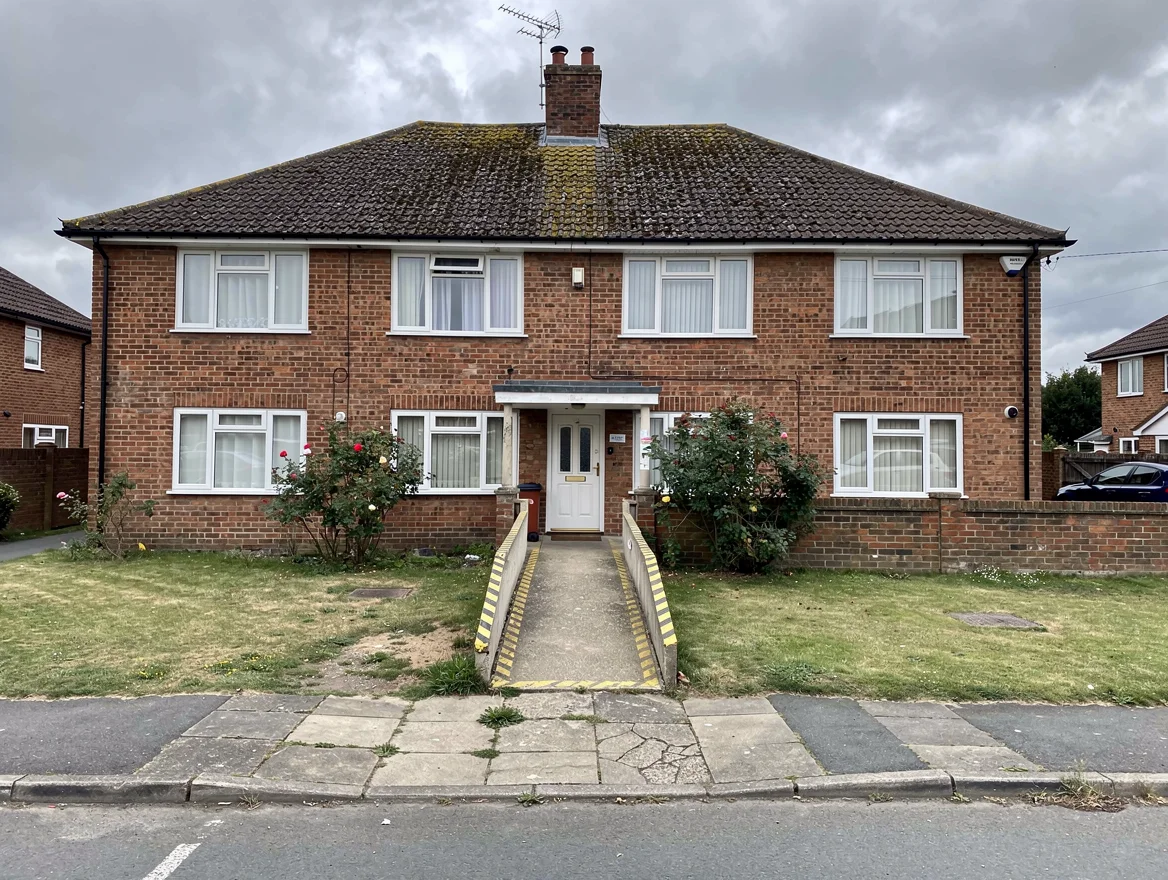 Small two-storey red-brick suburban care home with wheelchair-accessible ramp, mature front garden and bay windows, typical of Birmingham care homes sold at auction