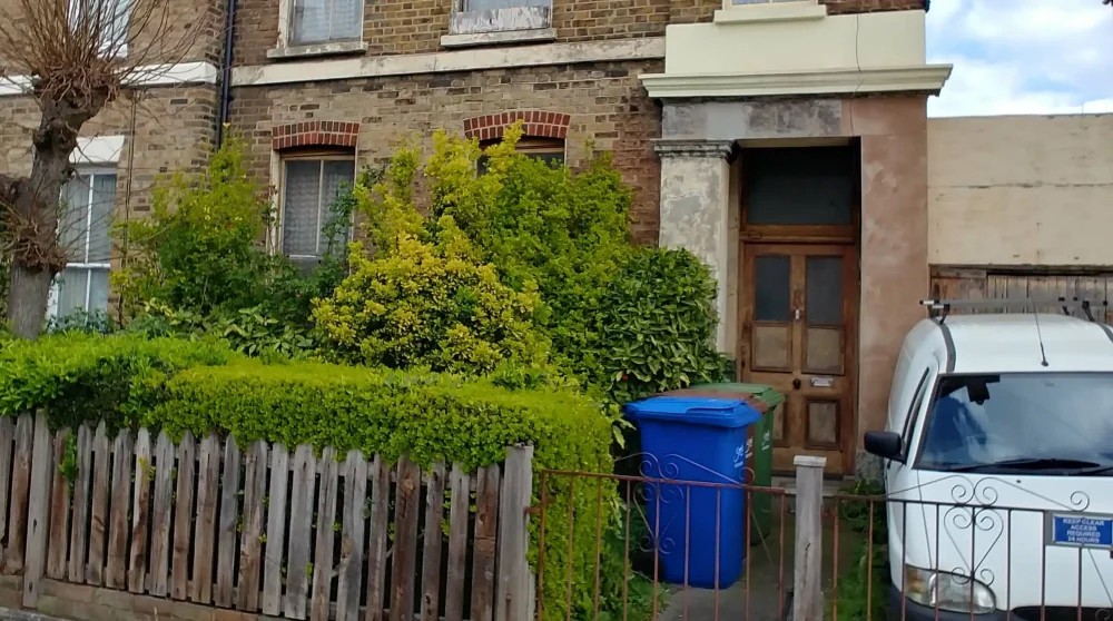 The overgrown front garden of a derelict house, a clear sign the property has been neglected and empty