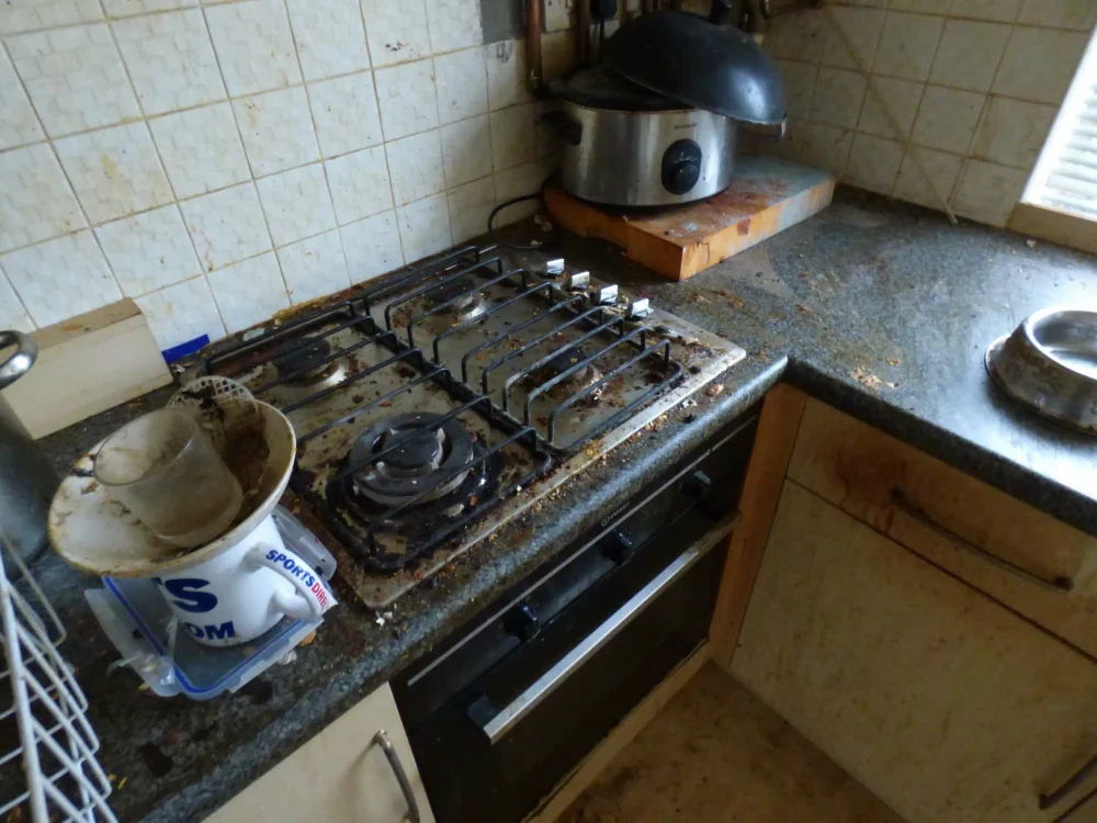 A dirty, greasy gas hob and worktop in a kitchen in a poor state