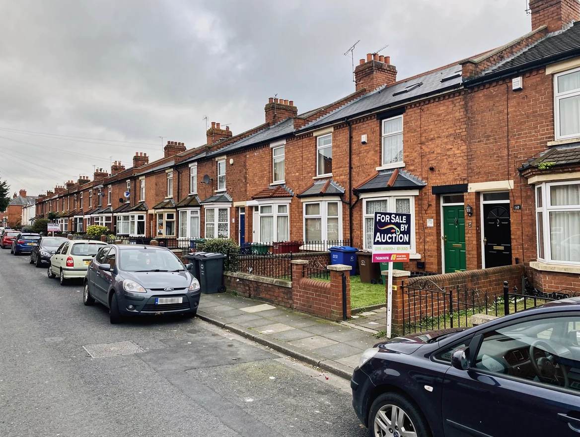 A 'For Sale by Auction' board outside red-brick houses on a Nottingham residential street