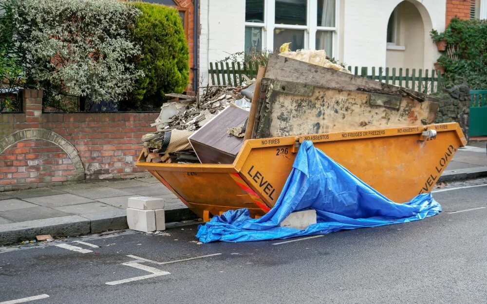 A builder's skip on a residential street filled with rubble and old fixtures cleared from a house being renovated