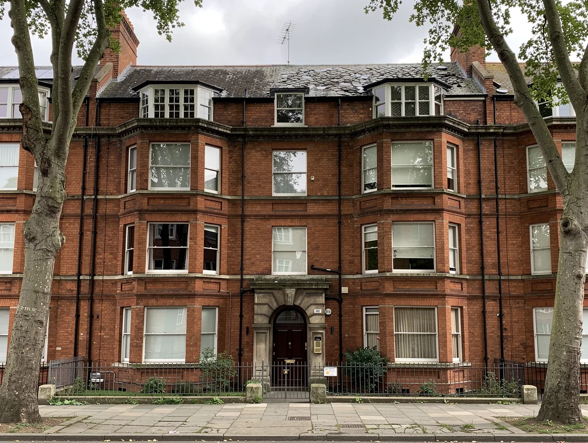 Edwardian red-brick London mansion block of leasehold flats with bay windows and a communal arched entrance, the kind of building where short-lease flats often come up for sale at auction