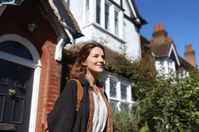 A woman walking away from a British house she has decided to sell
